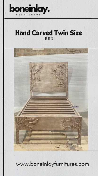 This video showcases a twin-size bed frame meticulously hand-carved with a detailed "Ornithology" theme, featuring birds perched among graceful tree branches on both the headboard and footboard. The solid wood frame has a soft, weathered finish that highlights the depth of the artisanal carvings and the organic wood grain. The camera pans across the sturdy slatted base and provides close-up views of the intricate wildlife motifs, emphasizing the blend of nature-inspired art and functional furniture design.