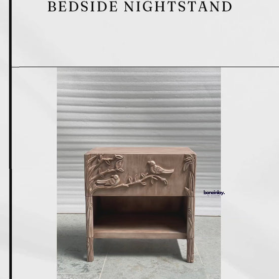 Hand-carved solid wood nightstand featuring a natural finish and an intricate ornithology relief. The single-drawer facade is masterfully sculpted with a detailed scene of birds perched on blossoming branches, doubling as a functional grip. This Bohemian-style bedside cabinet includes a spacious lower cubby and tapered legs with additional floral carvings, blending artisanal nature-inspired art with modern storage functionality.