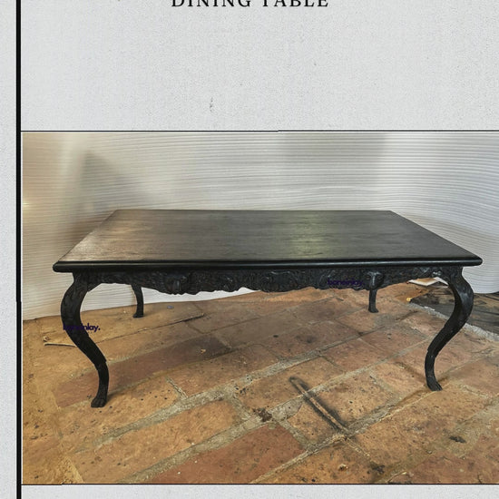 A large rectangular black dining table with a detailed hand-carved apron featuring a lion's head and forest animals. The table has four curved cabriole legs with ornate leaf carvings and ball-and-claw feet, all in a matte black finish.