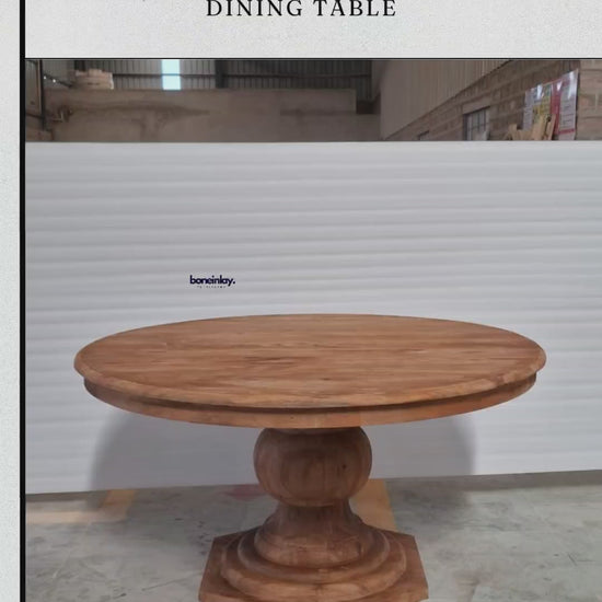 A factory video for a solid wood pedestal dining table with a natural honey finish. The video features a large, round tabletop supported by a single, chunky baluster-style pedestal base with an octagonal platform. It highlights the piece’s traditional silhouette and warm wood grain, advertising free worldwide delivery, custom options, and bulk discounts.