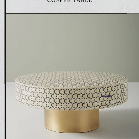 A round bone inlay Moroccan coffee table featuring an intricate, hand-placed geometric pattern in creamy white and soft grey tones. The circular tabletop rests on a solid cylindrical base with a brilliant gold-finished metal look, creating a sophisticated contrast between artisanal craft and contemporary luxury. Each small piece of bone is meticulously arranged to form a seamless, repeating star-like motif across the entire top and sides.