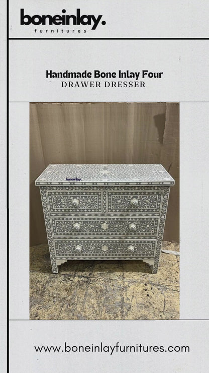 This elegant Handmade Bone Inlay Four-Drawer Dresser features a sophisticated gray finish with a classic white floral vine pattern. The unit includes two smaller top drawers and two larger bottom drawers, all accented with matching white knobs. Handcrafted with precision, the intricate design wraps around the entire piece, resting on four sturdy, decorative legs for a timeless aesthetic.