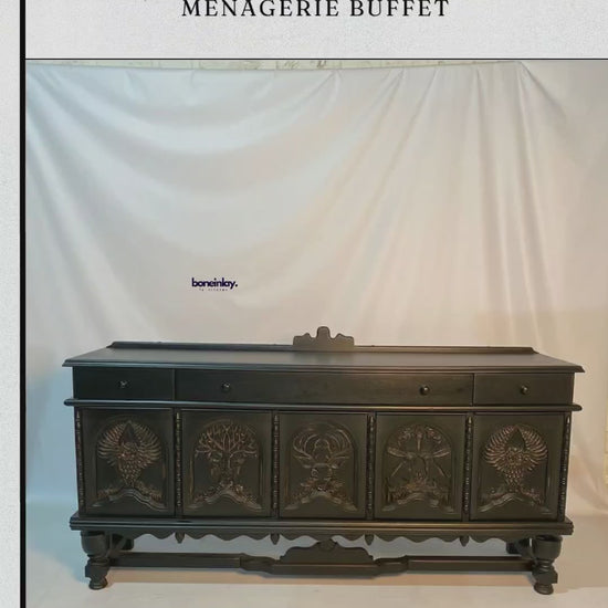 This artisan hand-carved solid wood sideboard is finished in a sophisticated matte black, featuring five arched door panels meticulously detailed with a wildlife menagerie motif. The carvings showcase intricate designs including an owl with outspread wings, a stag, and a central tree of life, all anchored by ornate turned legs and a decorative lower stretcher. This statement storage piece blends gothic elegance with traditional craftsmanship, making it a dramatic focal point for a dining room or entryway.