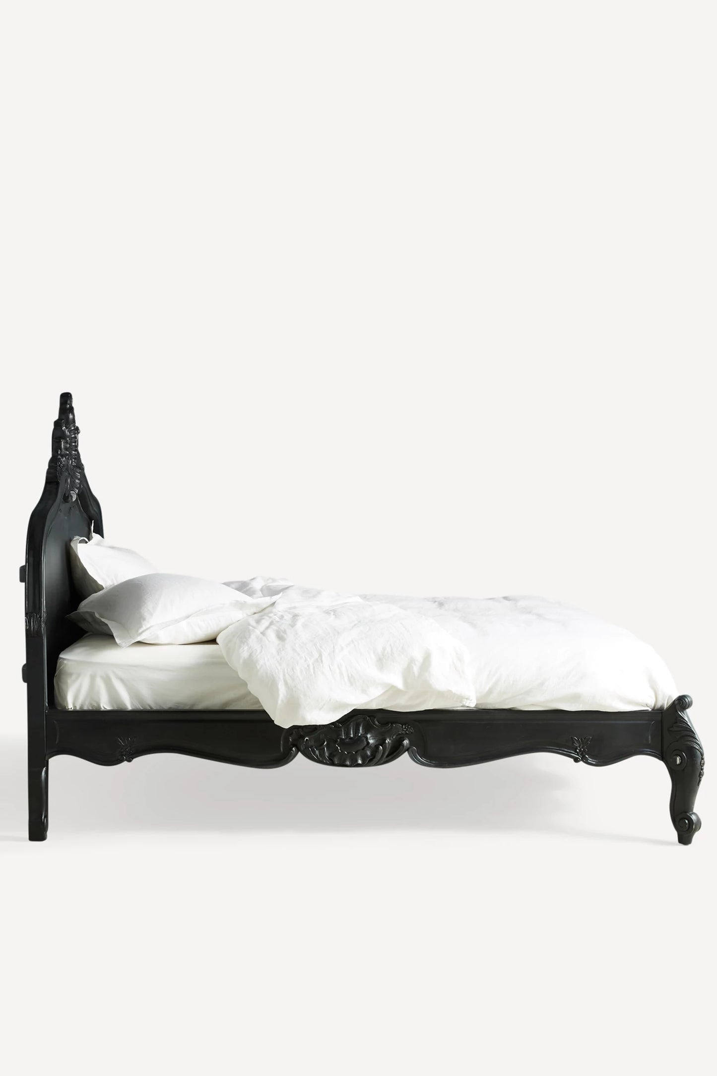A sleek side view of the Menara bed frame without bedding, showcasing the solid construction and the elegant silhouette of the arched headboard and footboard.