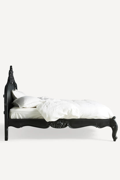 A sleek side view of the Menara bed frame without bedding, showcasing the solid construction and the elegant silhouette of the arched headboard and footboard.