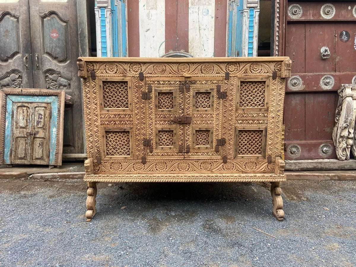 Front view of a vintage natural wooden dowry chest with floral carvings, lattice panels, and curved feet.