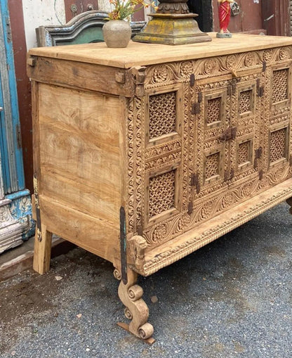 Close-up of the wooden dowry cabinet’s left side panel, floral carved front, and scroll-shaped front foot.