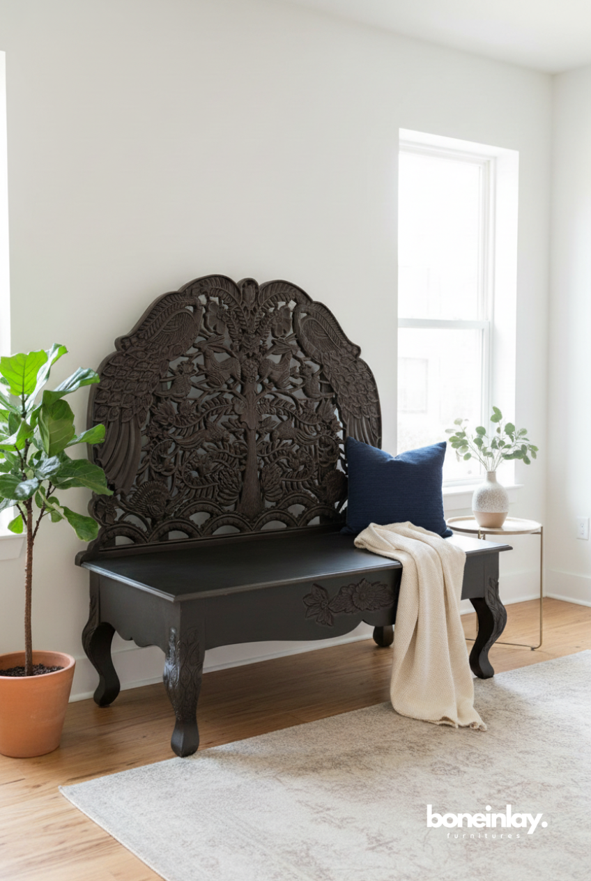 A dark-stained solid wood daybed bench with a highly detailed, hand-carved peacock motif on the backrest, placed in a bright, modern interior setting.