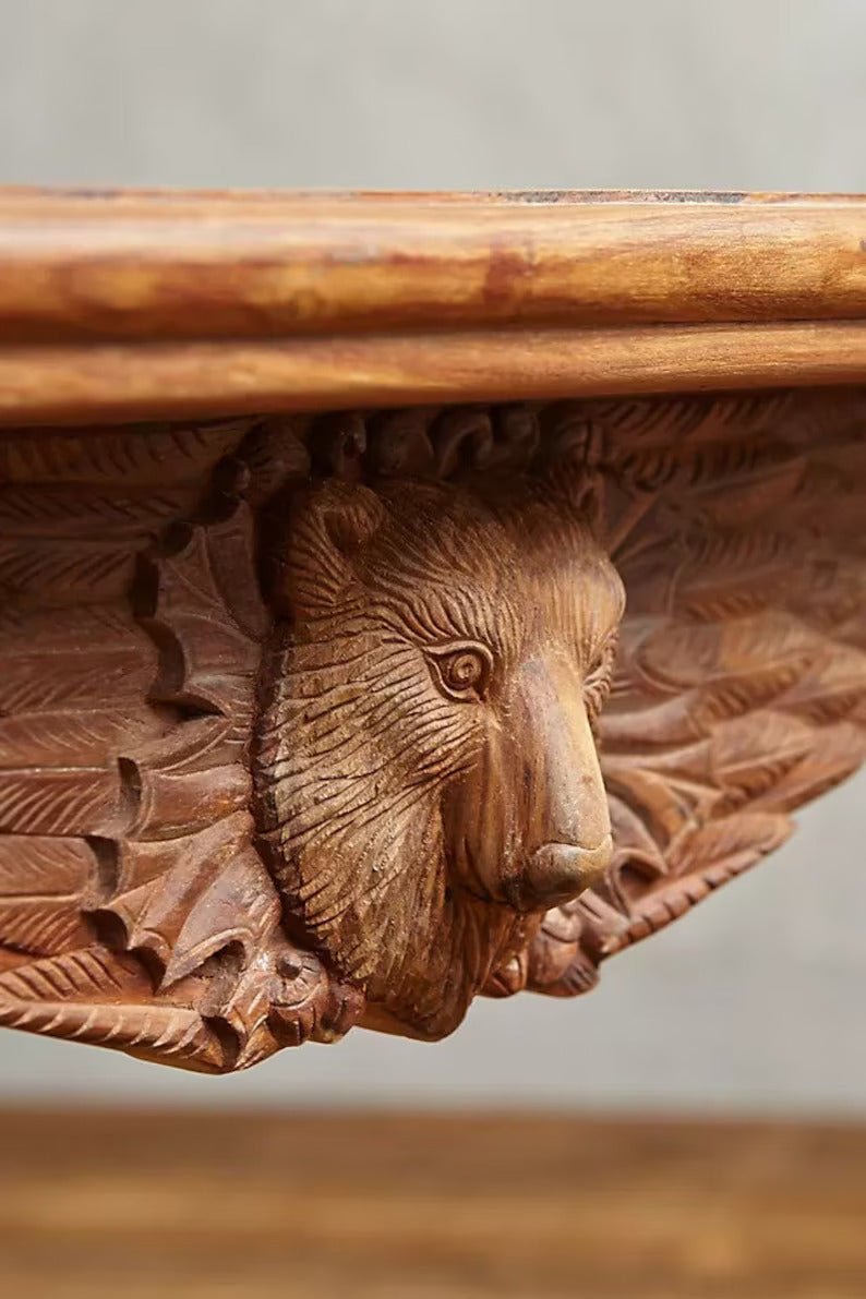 Animal motif dining table in warm solid wood, edge detail view showing a raised animal carving beneath the top.