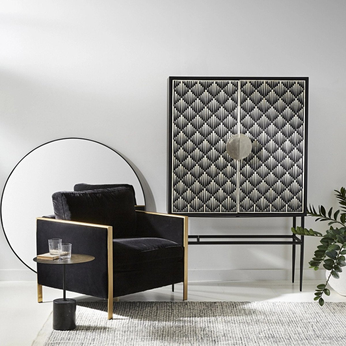 Black and white bone inlay bar cabinet with diamond chevron inlay pattern across two doors, oversized circular center pull handles, and a sleek black powder-coated iron base with tapered legs, shown on a white background