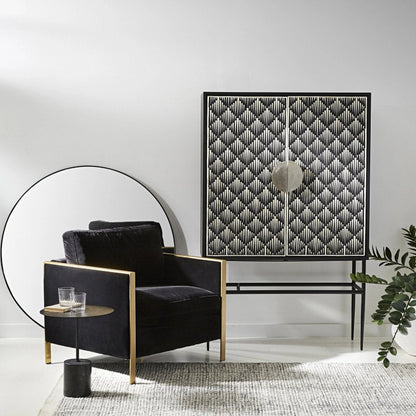 Black and white bone inlay bar cabinet with diamond chevron inlay pattern across two doors, oversized circular center pull handles, and a sleek black powder-coated iron base with tapered legs, shown on a white background