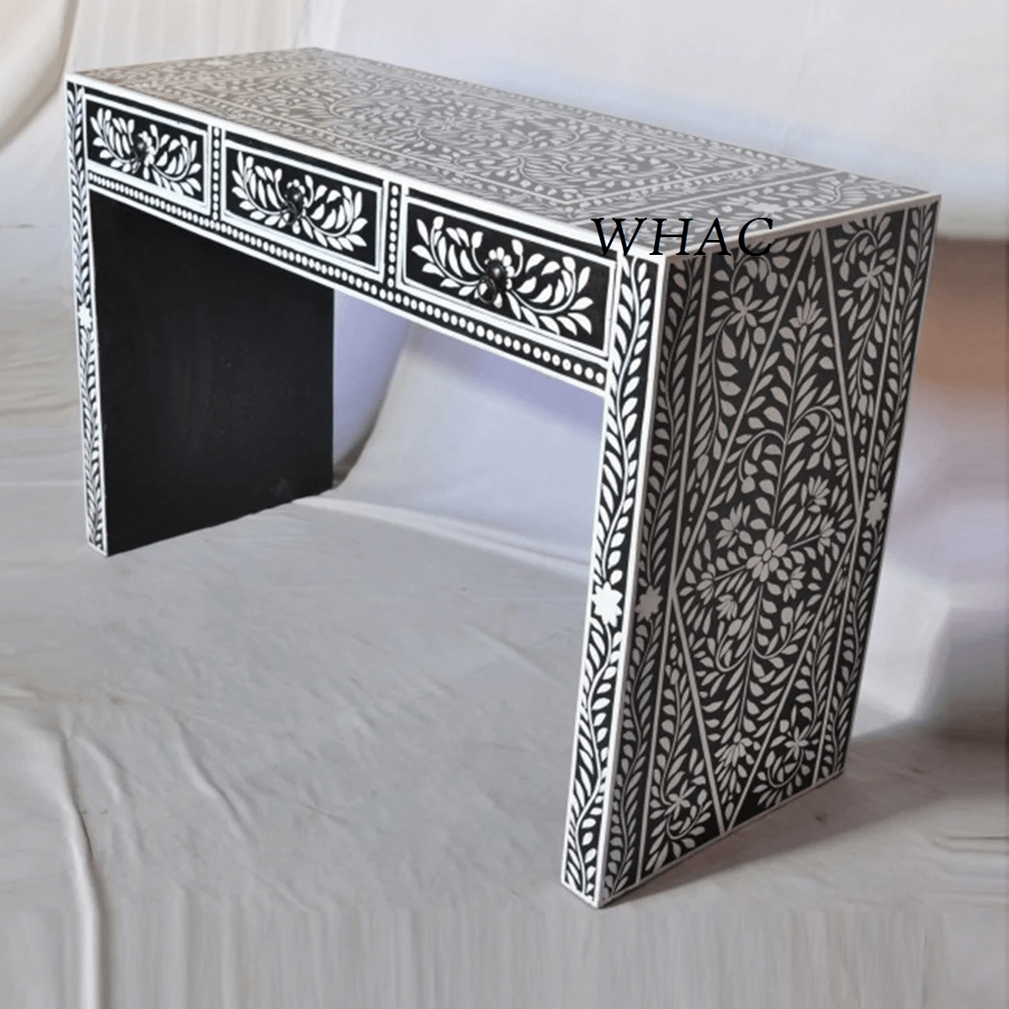 Black bone inlay console table with white vine and floral diagonal inlay pattern across the full leg panel and three front drawers with lotus motifs