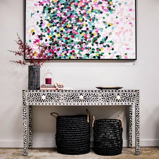Black floral bone inlay console table with 3 drawers and bone knobs, styled under colorful abstract wall art with wicker baskets, perfect for living room entryways.