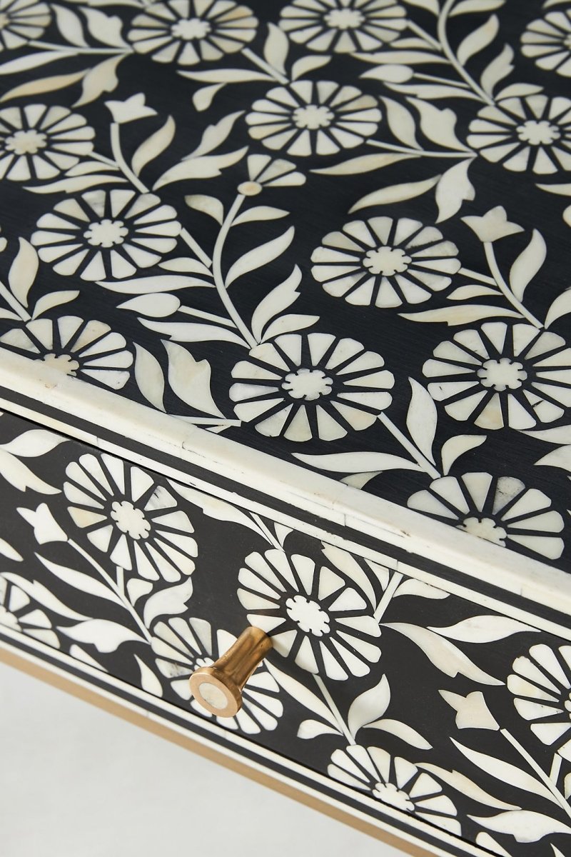 Black floral bone inlay hallway table in a close-up view, highlighting the white inlay pattern across the drawer fronts, the textured decorative surface, a round brass knob, and the detailed face of the three-drawer console table.