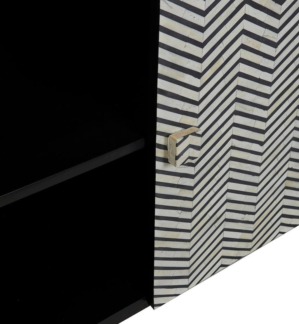 Macro detail of black and white chevron bone inlay pattern on cabinet door with handcrafted bone pull knob