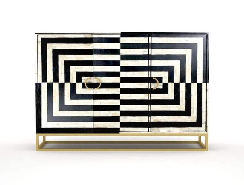 Black and white geometric optical illusion bone inlay buffet cabinet on gold sled base with ring pulls, photographed against clean white background