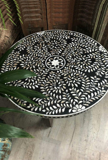 black and white bone inlay round coffee table shown from a top view, highlighting the floral design across the circular tabletop and the contrasting mosaic border around its edge, with the round silhouette clearly visible.