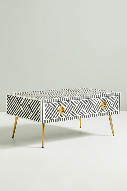 Black and white optical inlay cocktail table shown from a side three quarter angle with drawer closed