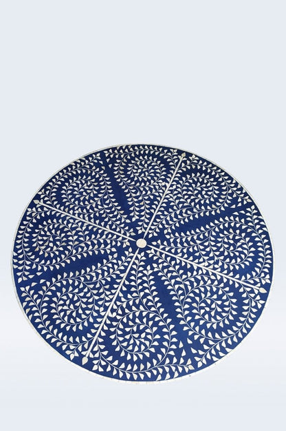 Top view of a round blue and ivory bone inlay coffee table showing the radiating floral vine and leaf motif across the tabletop, with hand-carved inlay arranged around the central starburst design and the circular edge visible. This view highlights the full surface.