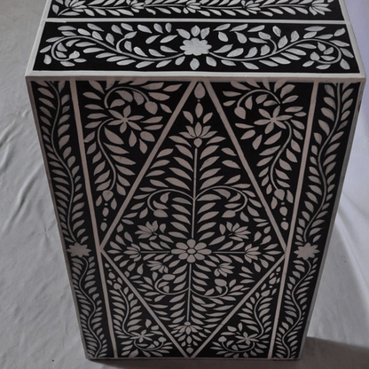 Detailed view of black bone inlay console table leg showing diamond-shaped vine and floral inlay pattern with handset white bone pieces on dark resin
