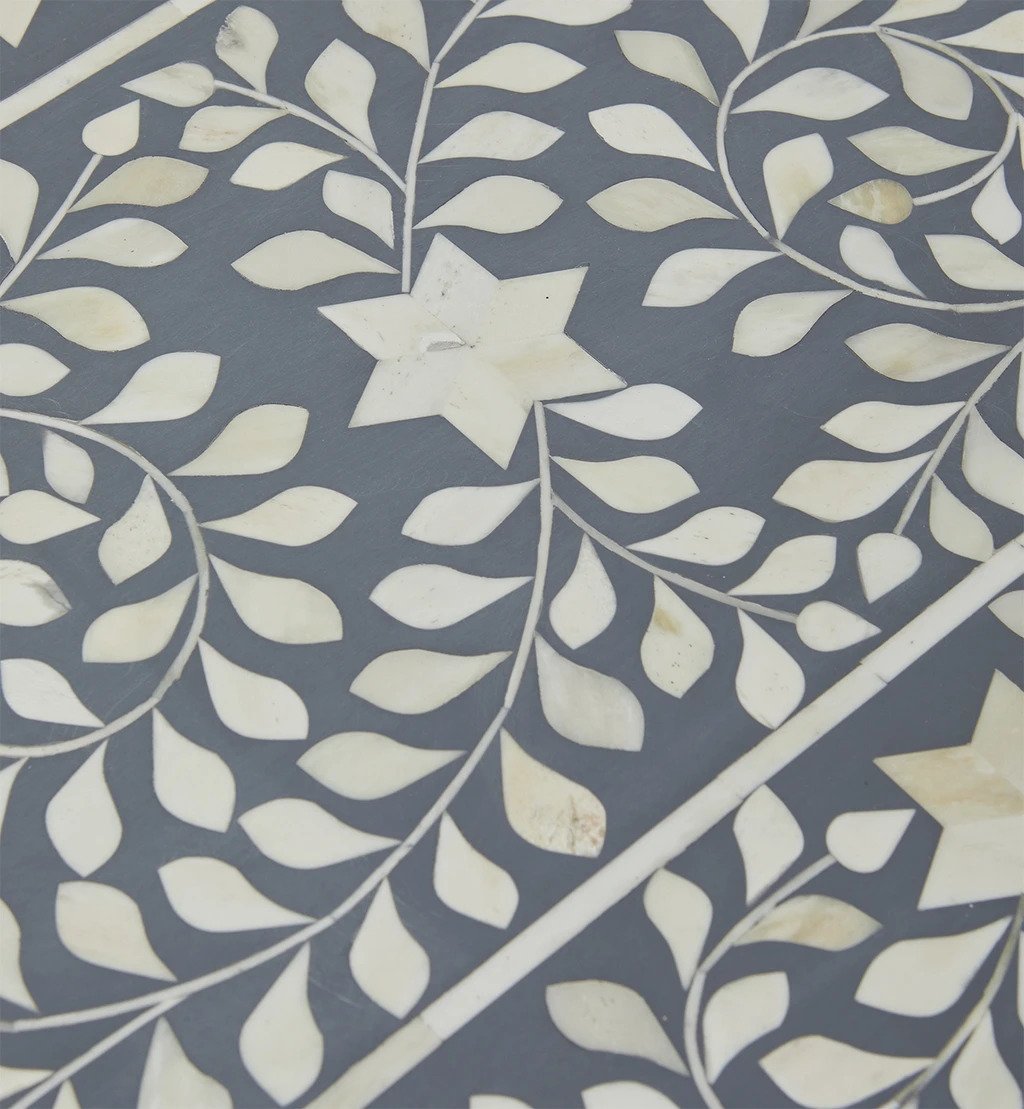 Close-up of hand-cut white bone inlay floral and star motif on a slate grey resin surface of a handcrafted Indian bone inlay console table