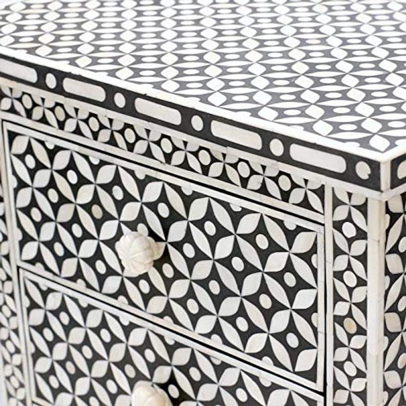 Detailed view of black and white bone inlay geometric eye pattern on handcrafted bedside table surface and drawer front with bone knobs