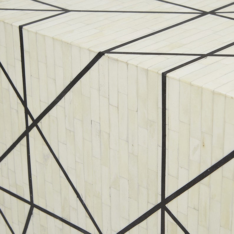 Macro detail of handcrafted ivory bone mosaic tile inlay with sharp black geometric lines on a luxury Indian artisan sideboard surface