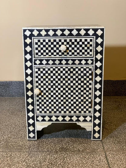 Black and white bone inlay wooden nightstand with checkerboard drawer and cabinet door panels, diamond floral border detailing, carved bone knobs, straight front-facing view