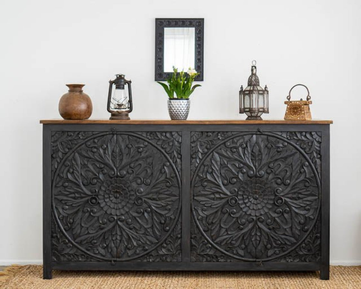 Carved Medallion Wood Credenza in black, shown in front view with ring pulls, flowers and a rectangular mirror.