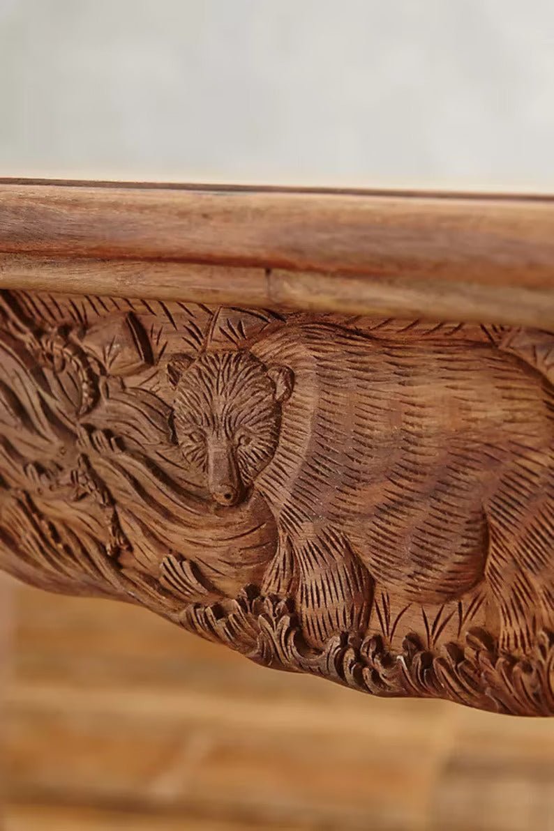 Carved Menagerie dining room table in warm solid wood, edge detail view showing animal motifs along the apron.