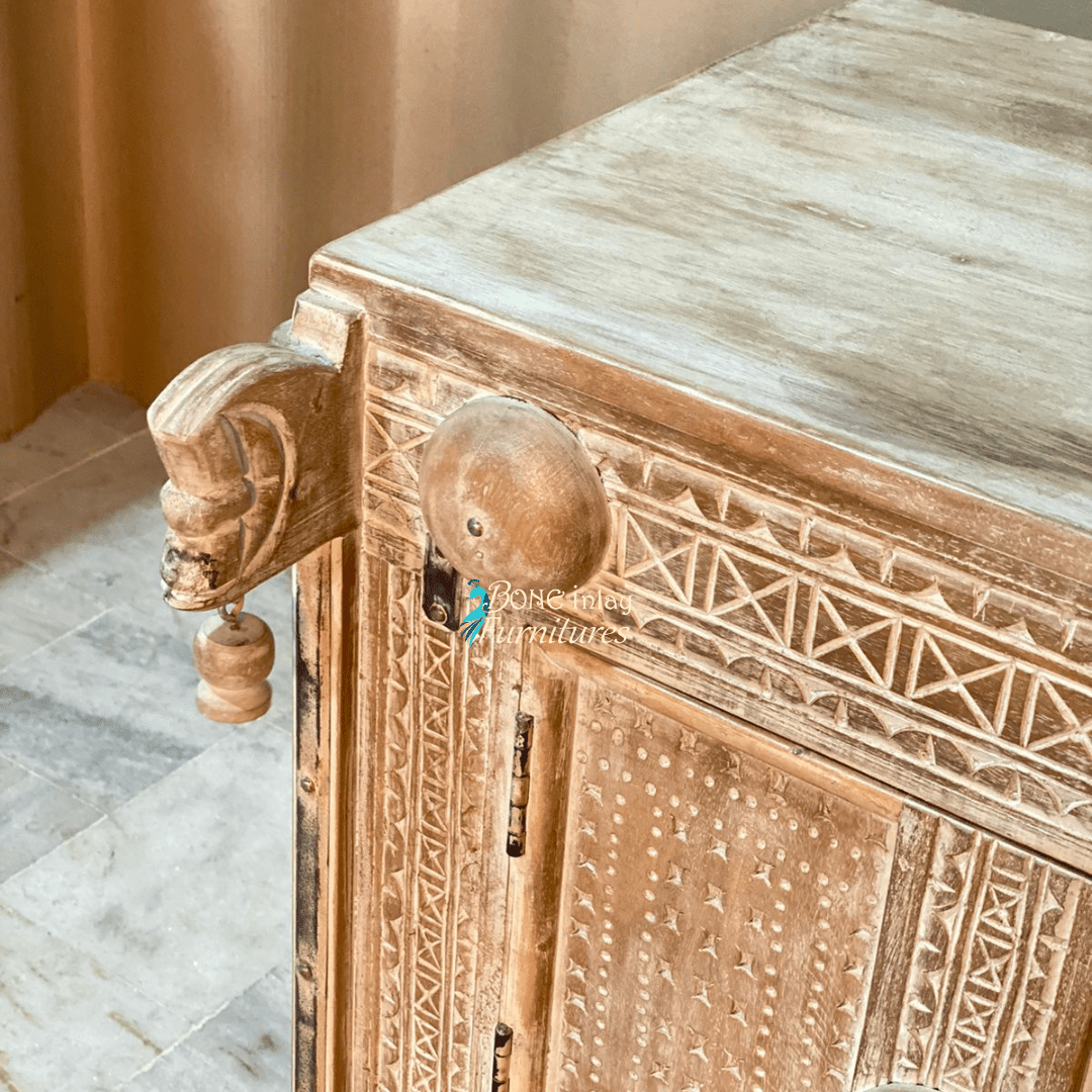 Hand-carved wood hope chest in a natural finish, corner detail view showing the left scroll, carved border and top.