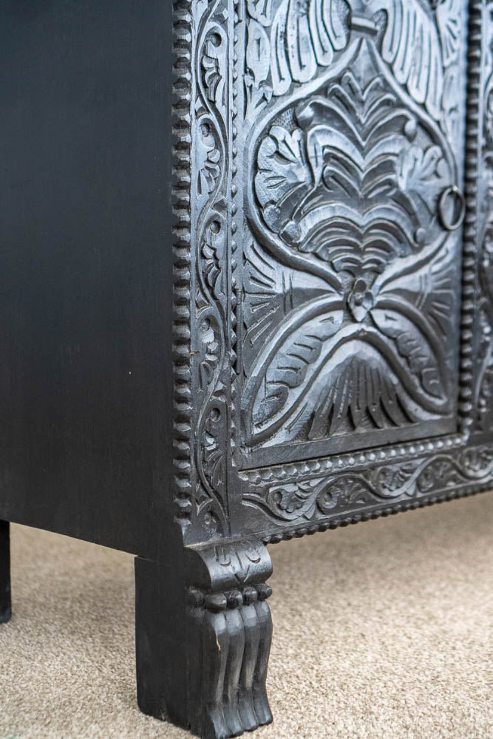 Carved Wooden Sideboard in charcoal, shown in a base detail view with the left front foot and lower door.