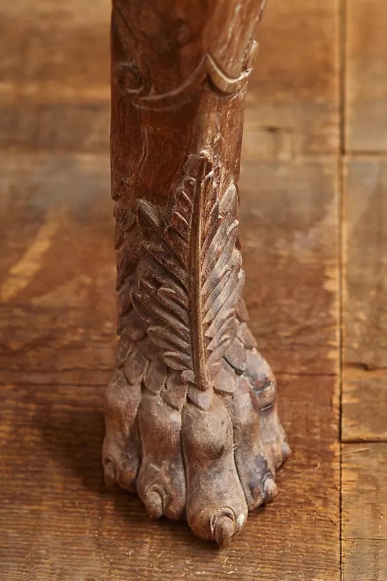 Claw foot dining room table in warm solid wood, close-up of leg showing sculpted details and a carved foot.