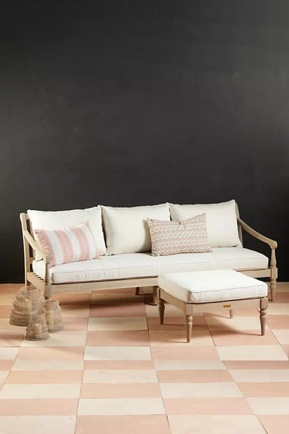 Cushioned wooden sofa with a solid frame, front view showing three back cushions and an ottoman against a dark wall.