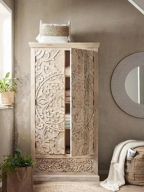 Farmhouse floral carved armoire in wood, styled in living room with a partly open door, plants and a round mirror.