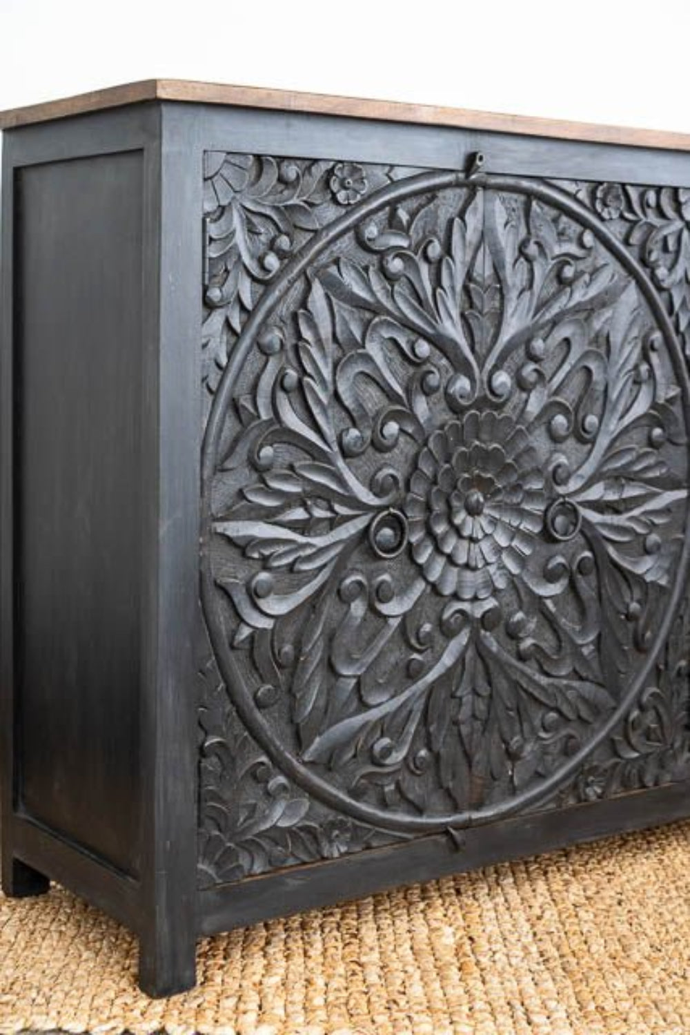 Floral Carved Sideboard in black wood, shown in corner detail view with a circular motif and recessed side.