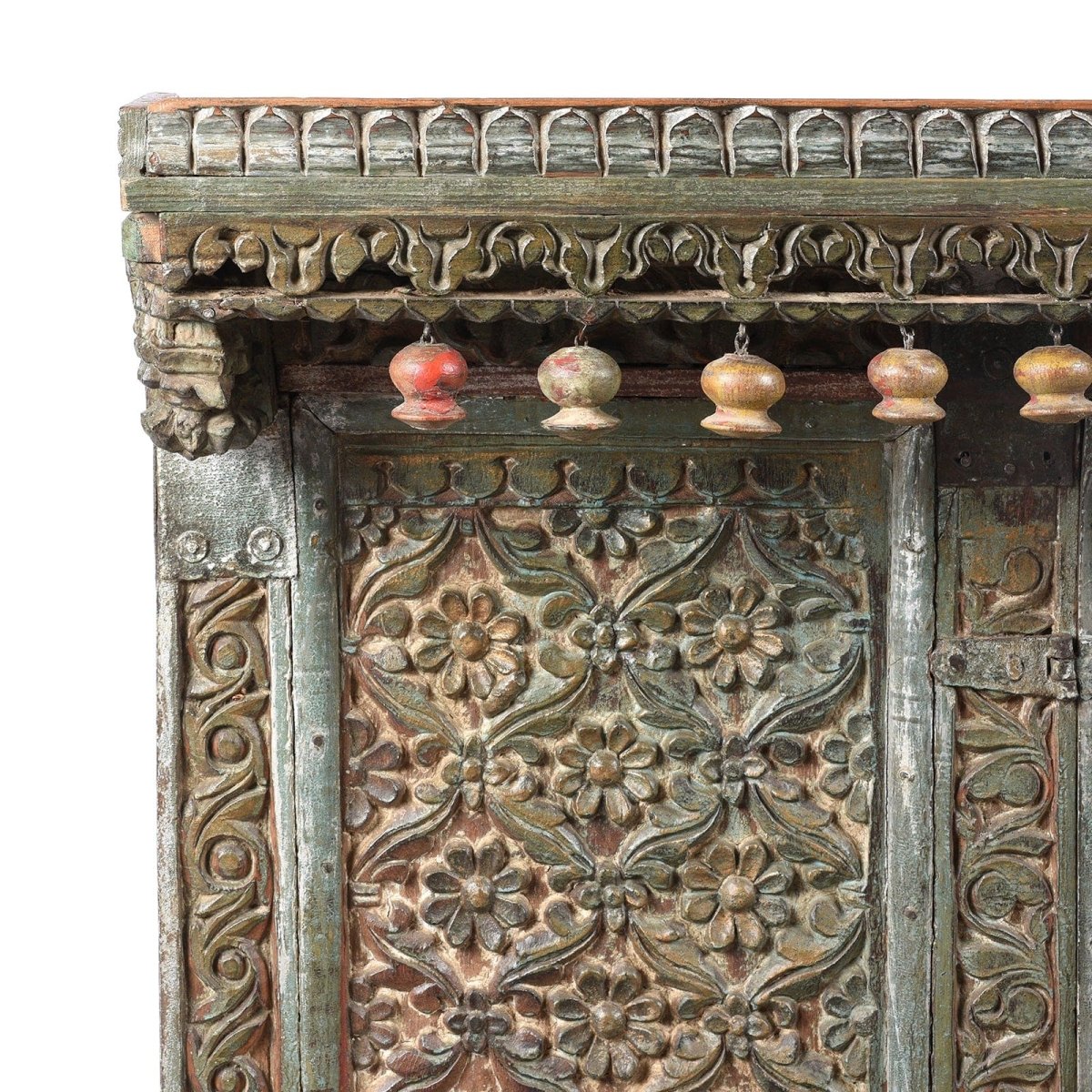 Floral carved wood credenza, corner detail view of the upper left panel, scrolling trim and colorful hanging ornaments.