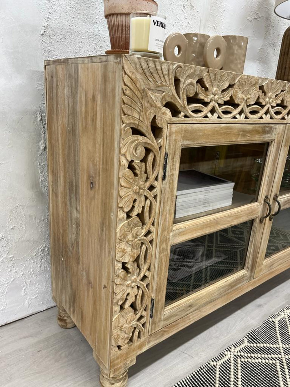Floral frame storage cabinet in rustic wood, corner detail view showing pierced carvings and the solid side panel.