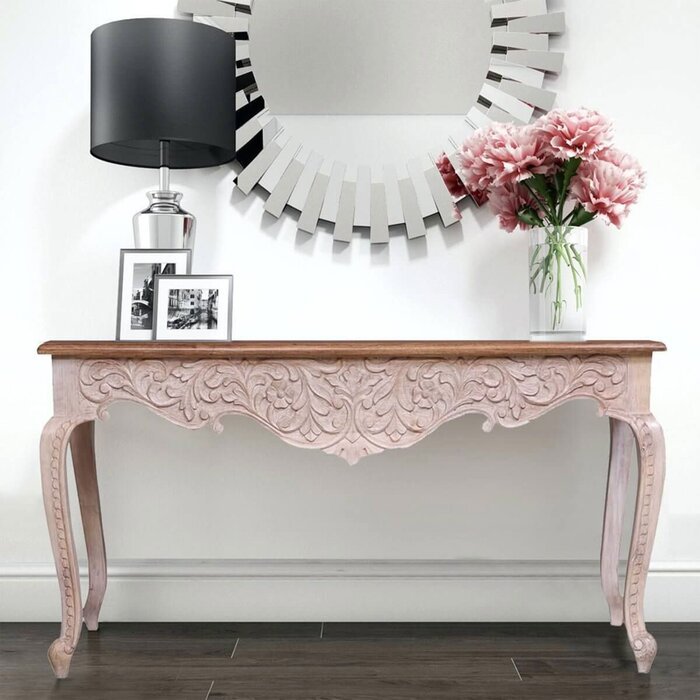 French Leg Sofa Table in rustic carved wood, styled in entryway with a black-shaded lamp and pink flowers.
