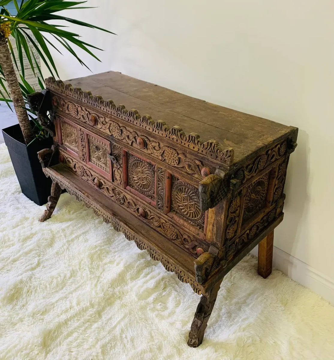 Geometric carved dowry chest in solid wood, top view from the right revealing the broad plank top and carved side.