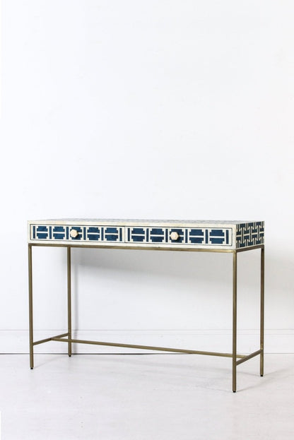 Left front angle of the dark blue bone inlay sofa table, showing the geometric lattice pattern over the rectangular top and two drawer fronts. The angled view shows the slim table depth, drawer layout, and gold-toned legs for a hallway, entryway, or office.
