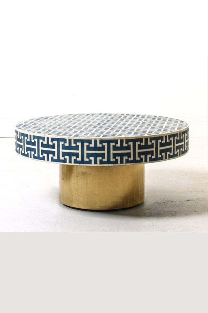 Blue bone inlay round coffee table shown in a front three-quarter view, with a deep blue and white geometric Greek key pattern across the circular top and a brass pedestal base visible beneath, photographed as a complete product view.
