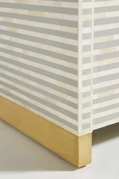 Close-up view of the handmade grey bone inlay buffet, showing the repeating horizontal stripe pattern and bone inlay detail on the curved sideboard surface. The frame focuses on the cabinet craftsmanship and grey inlay design.