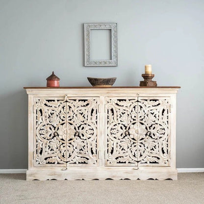 Hand-carved wooden buffet in a rustic finish, front view with floral doors, a bowl and candle beneath a wall frame.