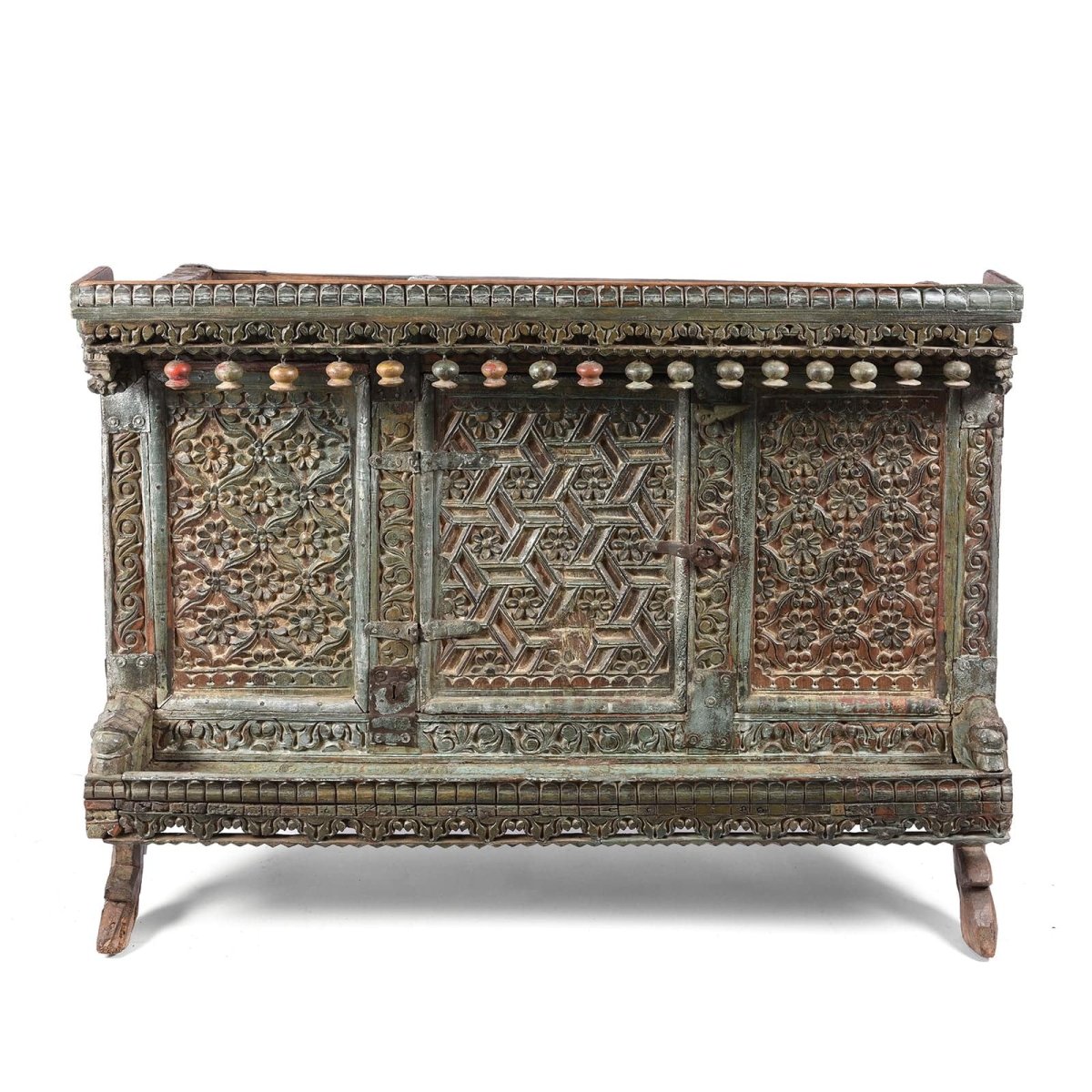 Hand carved wood sideboard, front view showing floral panels, a geometric center door and hanging wooden ornaments.