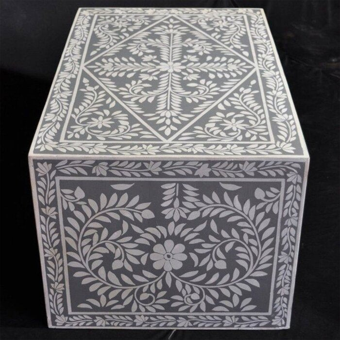 Handmade bone inlay center table in grey with dense white floral medallion and scrolling vine inlay pattern covering the full surface and apron, shot on dark background