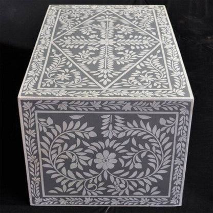 Handmade bone inlay center table in grey with dense white floral medallion and scrolling vine inlay pattern covering the full surface and apron, shot on dark background