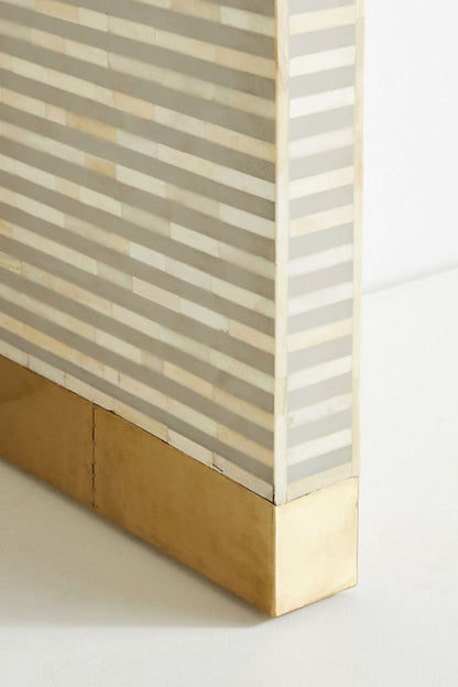 gray and white bone inlay console table, showing its curved waterfall profile, evenly spaced linear stripe pattern, slim rectangular top, and brushed gold brass-capped feet. The console table remains the main subject in the product view.