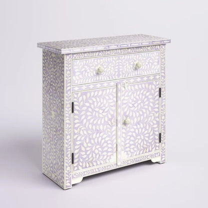 Handmade bone inlay cabinet in a soft ivory lavender finish with dense white leaf inlay pattern, wide single drawer with two bone knobs and double-door storage on a white studio background.