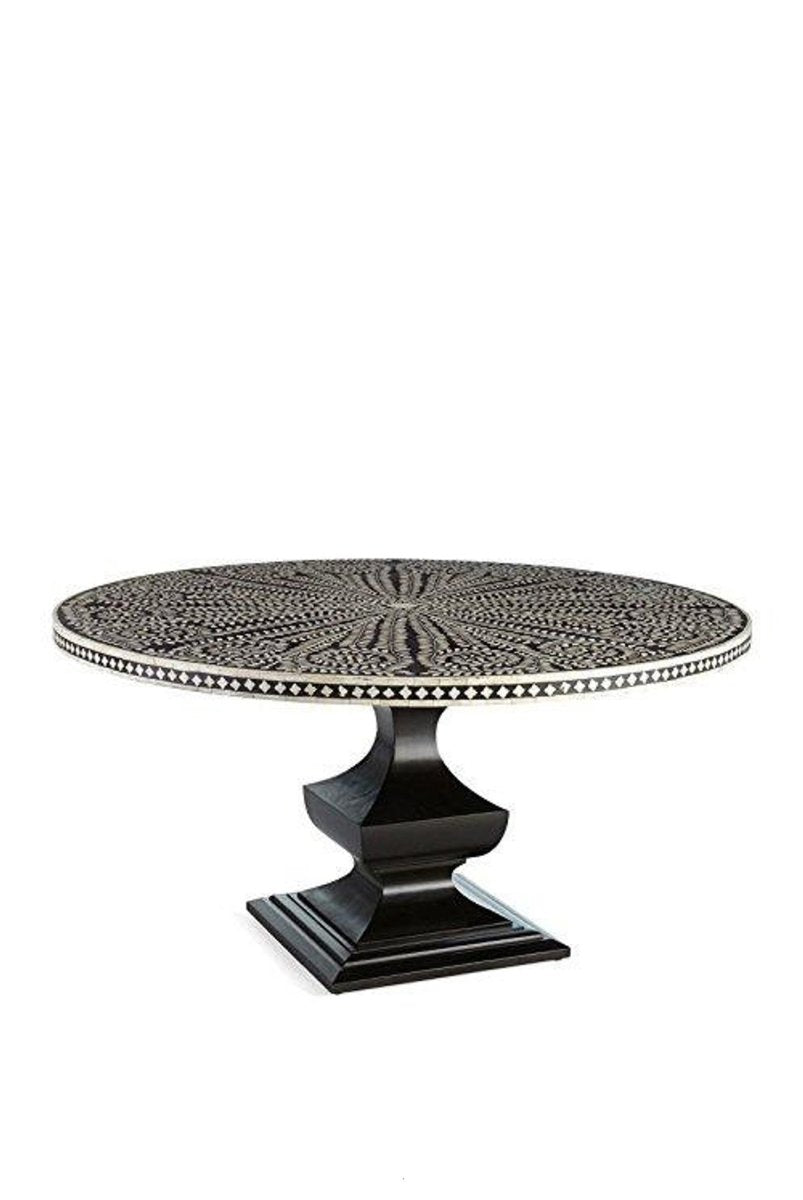 Front angle view of a handmade black and white bone inlay round dining table, showing the floral radial tabletop pattern, contrasting checkerboard border, and solid black geometric pedestal base as a complete dining room furniture piece.